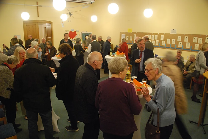 Menschen bei einer Kirchenveranstaltung mit Getränken und Snacks