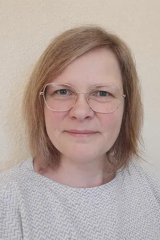 Zwei lächelnde Frauen mit Brillen, bunten Schals und lässiger Kleidung.