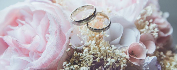 Zwei Eheringe ruhen zart auf einem wunderschönen Blumenarrangement.