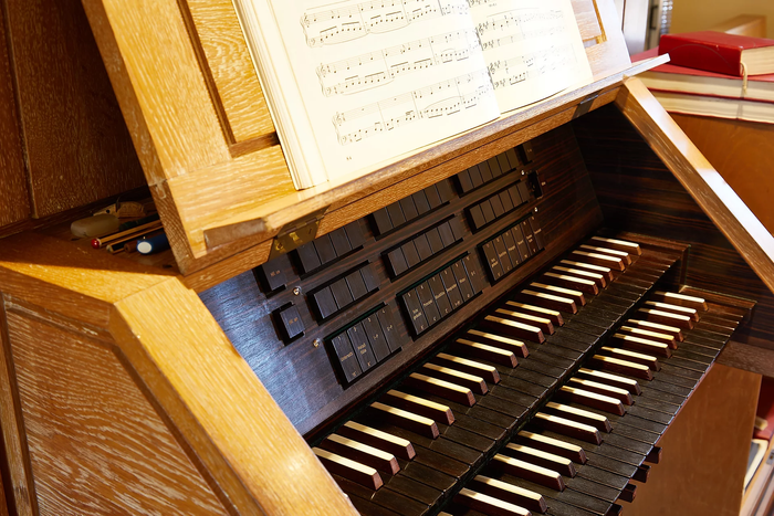 Holzorgelkonsole mit Notenblatt und mehreren Klaviaturen.